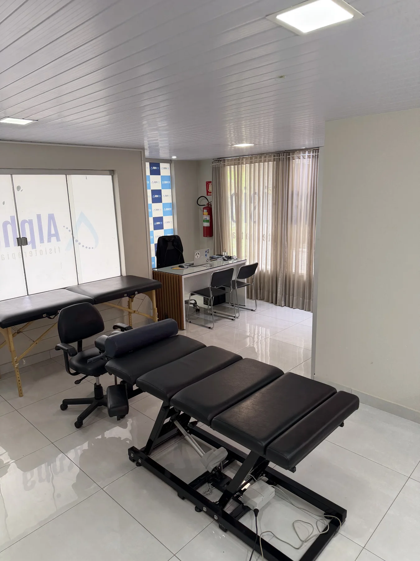 Consultório da Alphafisio, com mesa de avaliação e macas